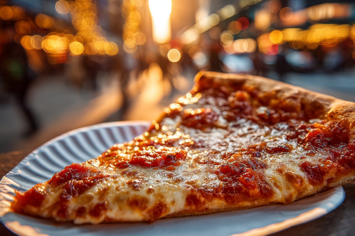kawałek pizzy w stylu nowojorskim na tacce na tle kolorowej ulicy