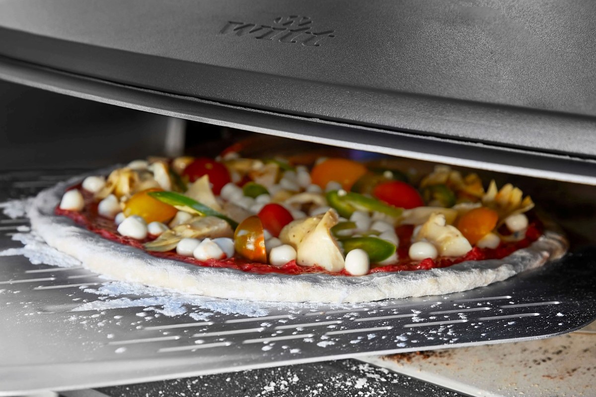 Moment wkładania pizzy na aluminiowej łopacie do pieca Witt